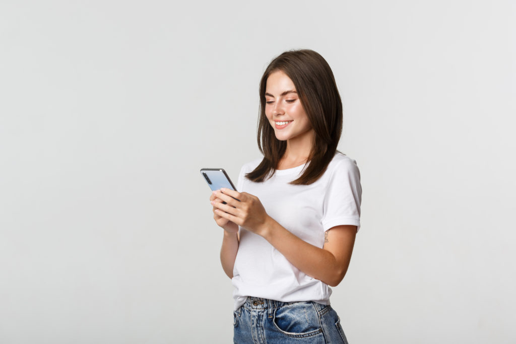 Mujer jóven sosteniendo su celular con alegría gracias a los consejos para aumentar la seguridad en smartphones